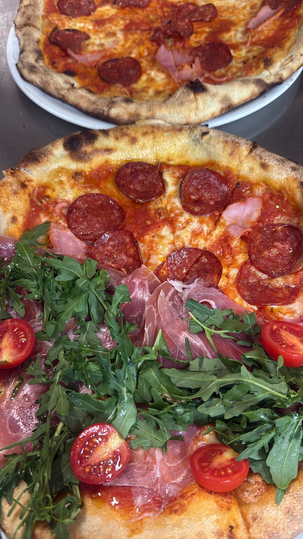 Pizza mit Salami, Parmaschinken, Rucola und Kirschtomaten